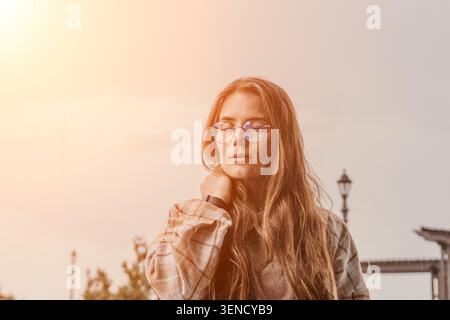 Woman glasses outdoor. Young female in eyeglasses standing outside during sunset with copy space Stock Photo