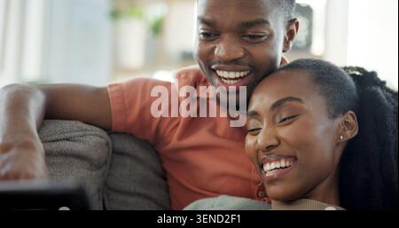 Laughing, couple and relax with tablet on couch, entertainment and streaming film with subscription. Black people, online and happy with partner in Stock Photo