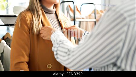 Fitting, coat and hands of designer with woman in store for shopping, discount or deal with tailor. Material, jacket and seamstress with female Stock Photo