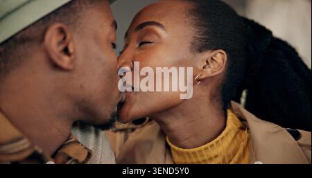 Love, cafe and black couple with kiss on date for celebration, anniversary or honeymoon on holiday. Vacation, happy woman and man in restaurant for Stock Photo