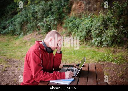 Man feeling stressed and exhausted from remote work, covering his face with hand Stock Photo