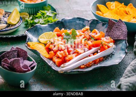 Traditional Mexican tomato salad with lime, onions and nachos with assorted dips Stock Photo