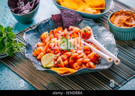Traditional Mexican tomato salad with lime, onions and nachos with assorted dips Stock Photo