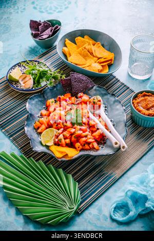 Traditional Mexican tomato salad with lime, onions and nachos with assorted dips Stock Photo