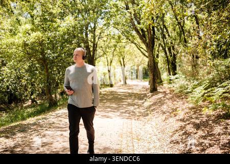 Man enjoying nature walk in forest while listening to music with headphones Stock Photo