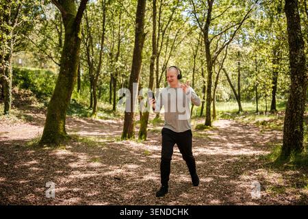 Man wearing headphones and holding smartphone while videoconferencing outdoors Stock Photo