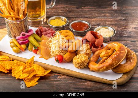 Crispy beer snack platter loaded with pretzels, sausages, nachos and assorted dips Stock Photo