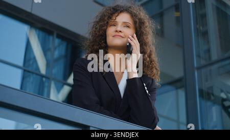 Caucasian business woman employer go out on balcony in office calling talking mobile phone businesswoman female girl executive talk smartphone Stock Photo