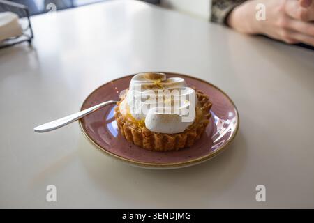 Lemon meringue tart on a pink plate with spoon Stock Photo