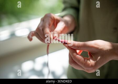 Woman hands holding showing smartphone charging cable with damaged winding near plug connection Stock Photo