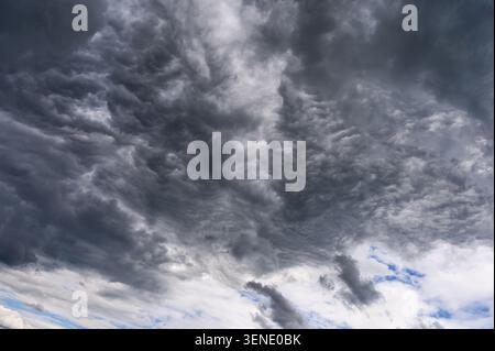 Heavy dark storm clouds covering the sky with patches of blue light. Stock Photo