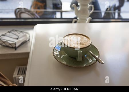 Fresh hot latte with latte art in a green ceramic cup Stock Photo
