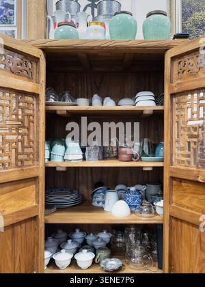Wooden cabinet filled with teapots cups and tea accessories in traditional Chinese interior Stock Photo