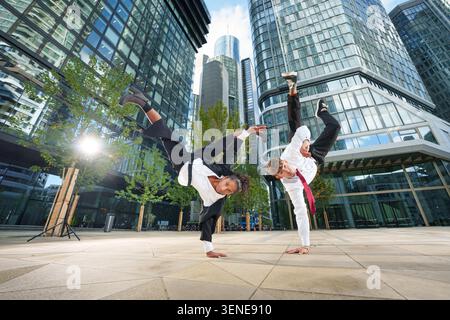 A group of multicultural young business people are breakdancing outdoors in business outfits. Stock Photo