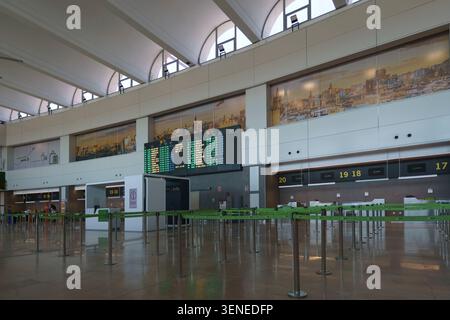 Empty check-in desks and flight departure information board inside the main terminal hall at Valencia Airport in Spain Stock Photo