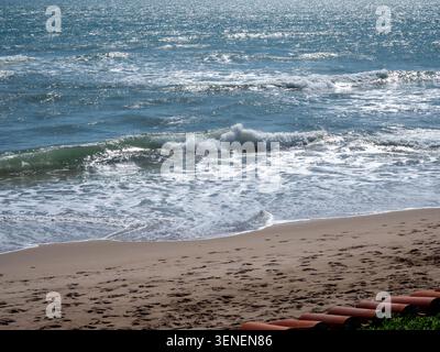Sunlit Mediterranean sea waves washing on sandy beach Stock Photo