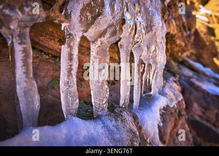 Close Up Icicle and Snow Formations on Red Rock in Winter Light Stock Photo