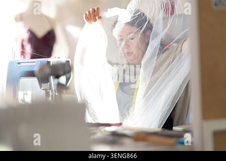Woman sewing and working with fabric in a sewing studio during daylight Stock Photo