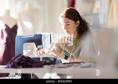 Sewing in a studio during daylight while focusing on fabric and patterns Stock Photo