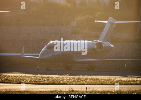 Private jet sits on runway during golden hour at local airport in the evening with sunlight reflecting off the surface Stock Photo