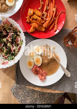 A healthy breakfast spread includes amaranth porridge, boiled eggs, beetroot hummus, baked vegetables, and a fresh salad. The meal is served on a neat Stock Photo