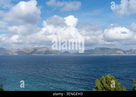 Dramatic cloudscape over deep blue sea and distant mountain coastline Stock Photo