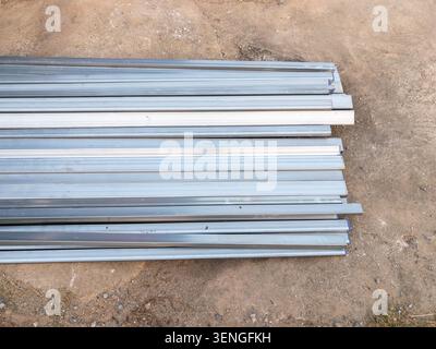 Galvanized metal tubes and square steel profiles at construction site background. Stock Photo