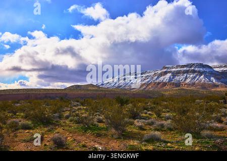 Snow Capped Red Rock Mountains and Desert Landscape Under Dramatic Cloudy Sky Stock Photo