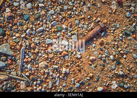 Rusty Screw On Gravel Texture With Earthy Stones And Sand Stock Photo