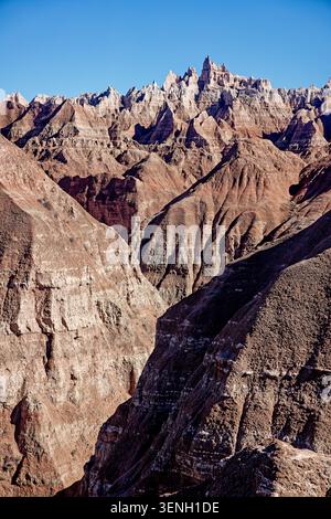 Expansive view of arid, eroded mountain ranges of Badlands National Park with sharp peaks and deep canyons bathed in sunlight and shadow Stock Photo