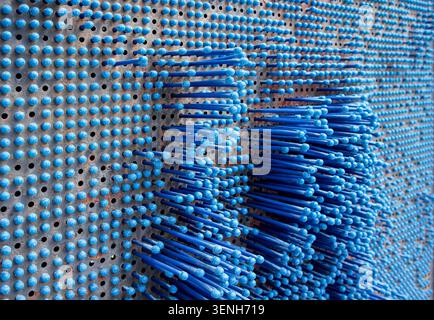 Abstract installation of blue pins and dots on a wall, creating a textured visual effect in a modern indoor environment Stock Photo