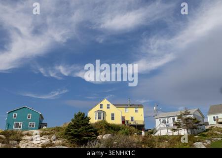 Colourful coastal homes perched on granite shoreline in Nova Scotia Canada beneath dramatic cloud formations creating a striking Atlantic maritime lan Stock Photo