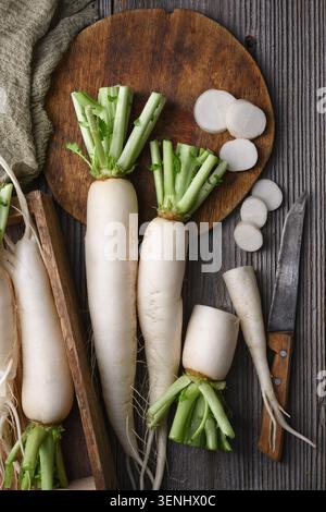 Whole and sliced daikon radish on wooden surface, white radish, organic vegetables Stock Photo