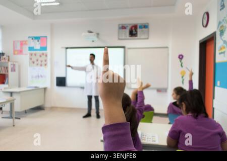 Close-up of a schoolgirl hand raised to ask a question in a classroom. Stock Photo