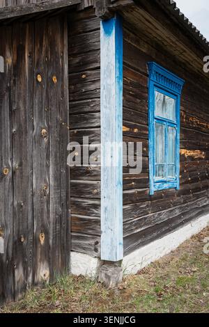 Antique rustic log cabin wall featuring beautiful bright blue vintage window shutter and frame. Traditional slavic rural architecture Stock Photo