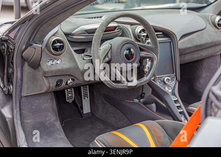 Luxury sports car interior emphasizing sleek design with suede steering wheel and dashboard contrasting dark fabric seats with orange stitching showca Stock Photo