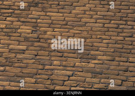 Aged brick wall, rough texture, golden hour lighting, running bond pattern, historical significance, architectural interest, emphasizing depth and det Stock Photo