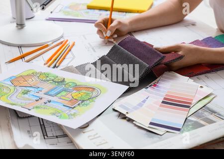 Interior designer working on home renovation project with fabric swatches and architectural plans Stock Photo