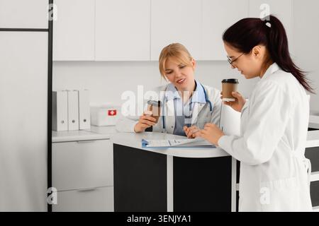 Medical professionals collaborating on patient care, discussing healthcare information, and reviewing documents in a modern clinic Stock Photo