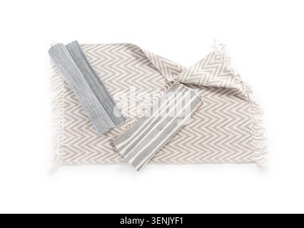 Neutral chevron patterned woven rug with fringed edges and two rolled striped fabric samples, the items are isolated on a clean white background, thei Stock Photo