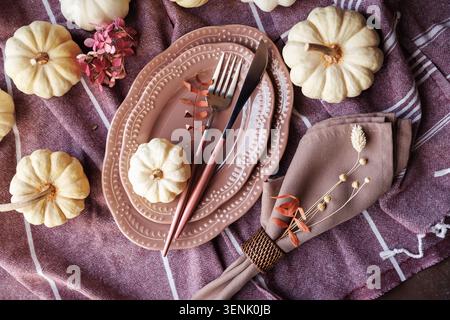 Stylish fall table decor with pink plates and rustic pumpkins Stock Photo