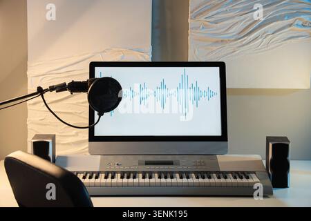 Home recording studio setup with microphone, computer monitor displaying audio waveform, and electronic keyboard Stock Photo