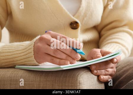 Womans hands writing notes in a spiral notebook with a blue pen, education and learning concept, close-up view Stock Photo