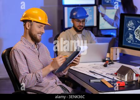 Male engineer with clipboard working in office at night Stock Photo