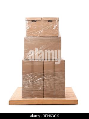 Stacked cardboard boxes wrapped in clear plastic film on wooden pallet, shipping and moving logistics Stock Photo