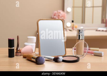 Different cosmetics, makeup brushes and mirror on table in living room, closeup Stock Photo