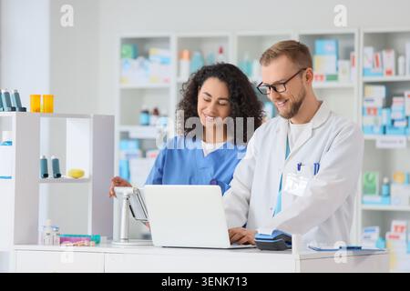 Pharmacist and pharmacy technician collaborating on laptop for prescription management and customer service, the background shows shelves filled with Stock Photo