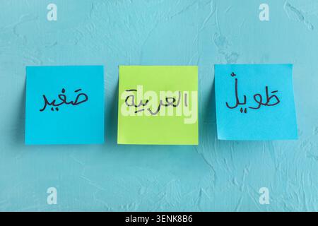Arabic language learning with sticky notes displaying words for small, arabic, and long on blue background Stock Photo