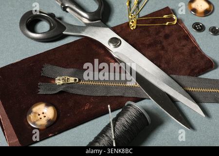Sewing and tailoring tools with fabric, zipper, thread, buttons, and scissors for crafting and fashion design Stock Photo