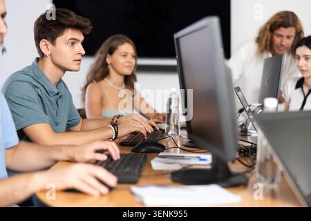 Focused guy studying in computer lab with fellow students Stock Photo